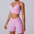 Pink workout set with halter neck sports bra and high-waisted biker shorts, featuring belly button piercing detail