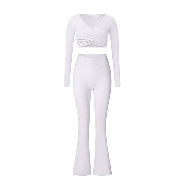 White athletic two-piece set with long sleeve wrap top and shorts, displaying minimalist design and form-fitting style