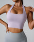 Model in lilac halter sports bra with scoop neck, paired with light gray high-waist leggings, photographed against neutral backdrop