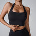 Model wearing black halter-style sports bra with square neckline and matching high-waist leggings against light gray background