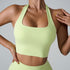 Model in pale yellow halter sports bra and matching high-waist leggings, photographed against light gray studio background