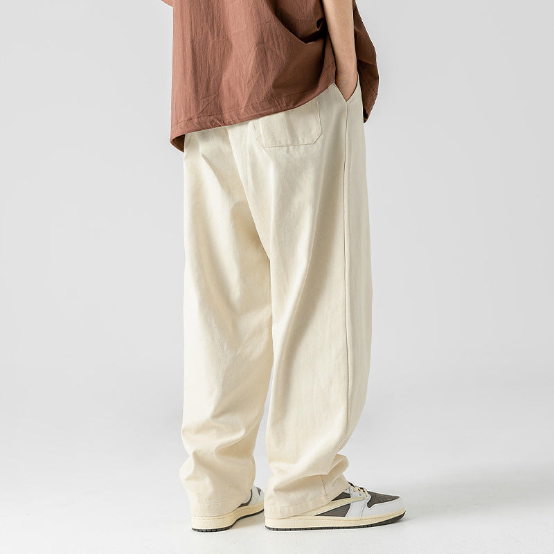 A model is wearing off-white wide-leg drawstring pants and a brown shirt, captured from the back while standing against a plain background