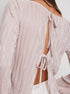 Close-up of pink blouse back detail showing pleated texture and two decorative bow ties