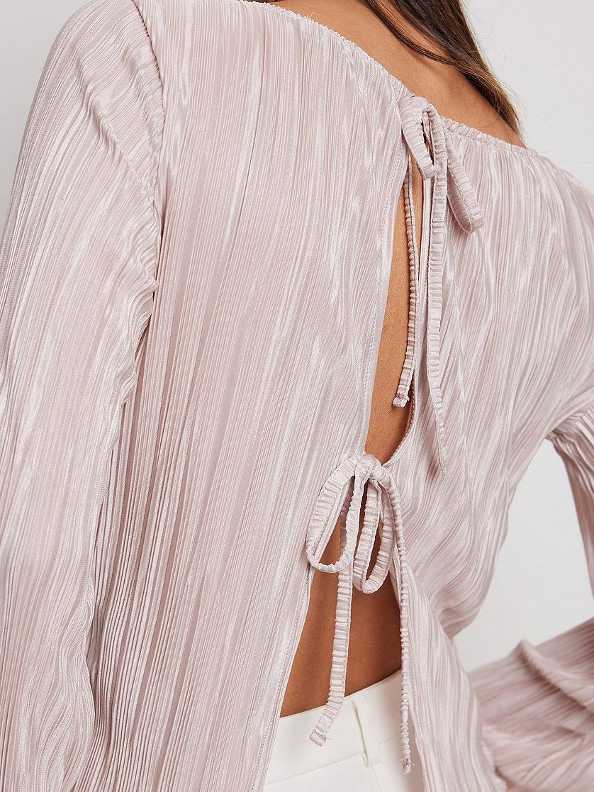 Close-up of pink blouse back detail showing pleated texture and two decorative bow ties