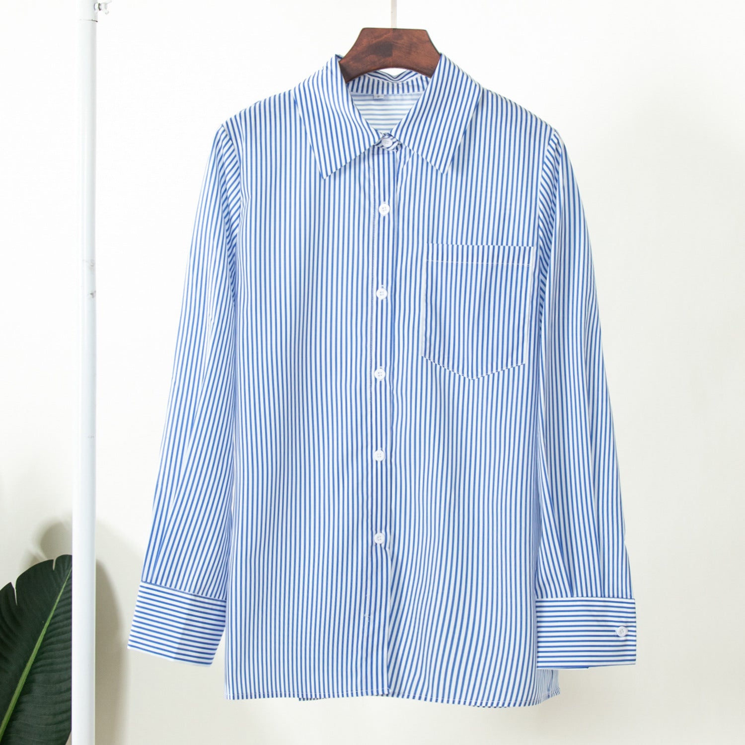 Blue and white striped button-up shirt on wooden hanger