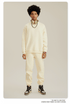 Male model in cream sweatsuit set with gold headphones draped around neck, silver chain necklace and brown/white Jordan sneakers