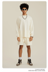 Man with afro in white sweatshirt and shorts set with sunglasses, chain necklace and sneakers