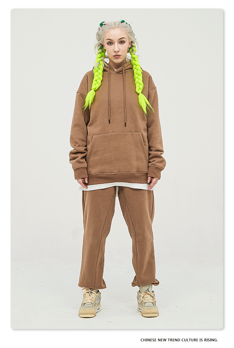 Model with platinum hair and neon yellow braids wearing a tan/camel sweatsuit with oversized hoodie and matching joggers