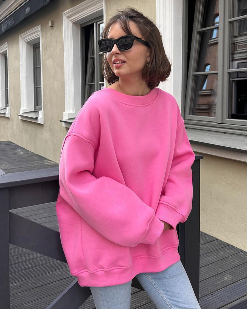 Oversized pink sweatshirt with drop shoulders paired with light jeans and black sunglasses