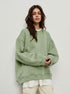 Sage green oversized sweatshirt layered over white top with cream cargo pants