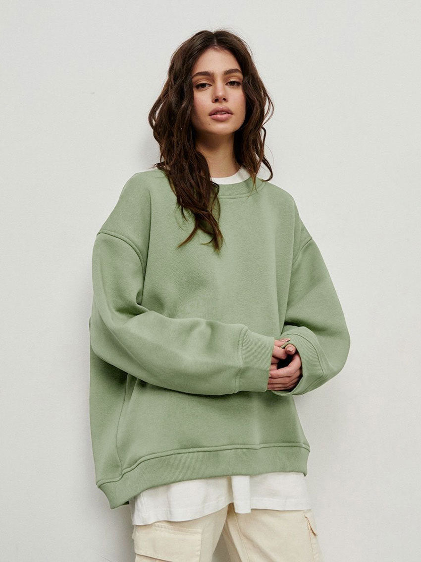 Sage green oversized sweatshirt layered over white top with cream cargo pants