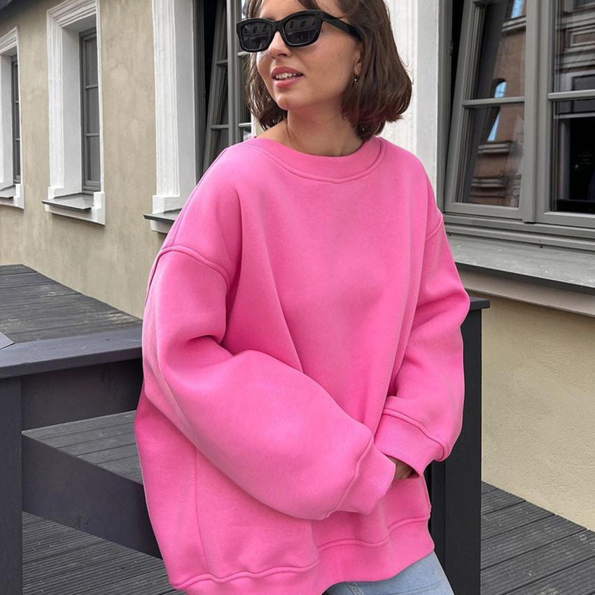 Oversized pink sweatshirt with drop shoulders paired with light jeans and black sunglasses