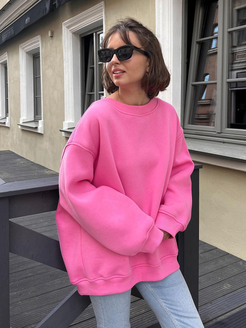 Oversized pink sweatshirt with drop shoulders paired with light jeans and black sunglasses