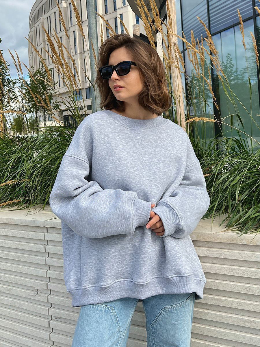 Heather gray oversized sweatshirt worn with sunglasses against urban landscaping with ornamental grasses