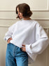 White oversized crewneck sweatshirt with balloon sleeves paired with classic blue jeans