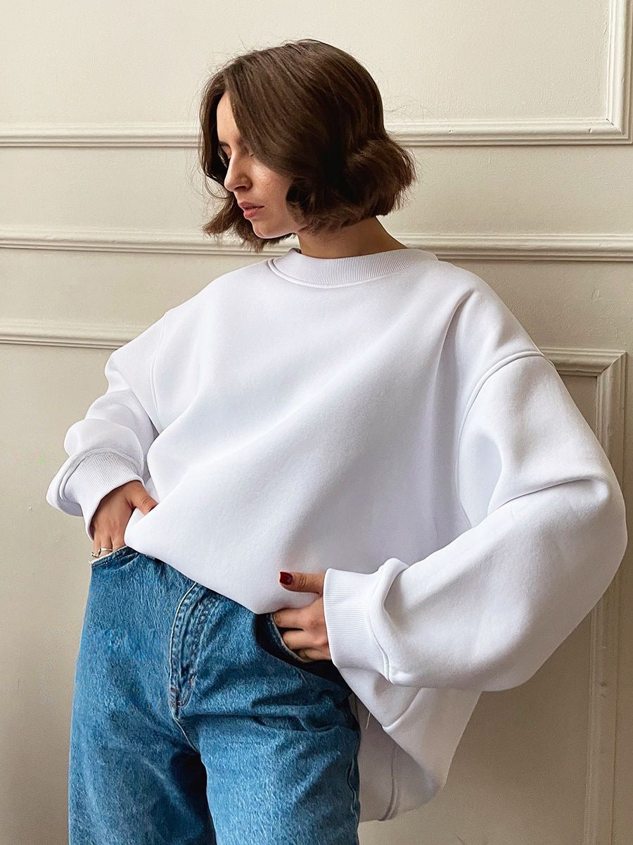 White oversized crewneck sweatshirt with balloon sleeves paired with classic blue jeans
