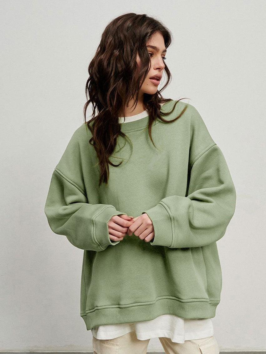 Sage green oversized sweatshirt layered over white tee, styled with relaxed-fit casual pants