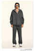 Model in dark gray tracksuit with white sunglasses, silver chains and white athletic shoes