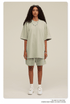 Female model in light beige oversized t-shirt and matching shorts set, styled with beaded necklace, sunglasses and white sneakers