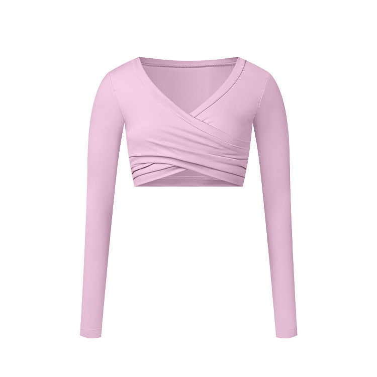 A soft pink long-sleeve wrap crop top with V-neckline and crossed ruching detail, shown flat against white background