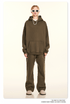 Model in olive green hoodie and sweatpants with white sunglasses and pearl necklace against neutral background