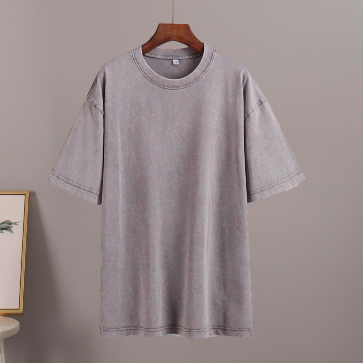 Gray t-shirt on a hanger against a plain background