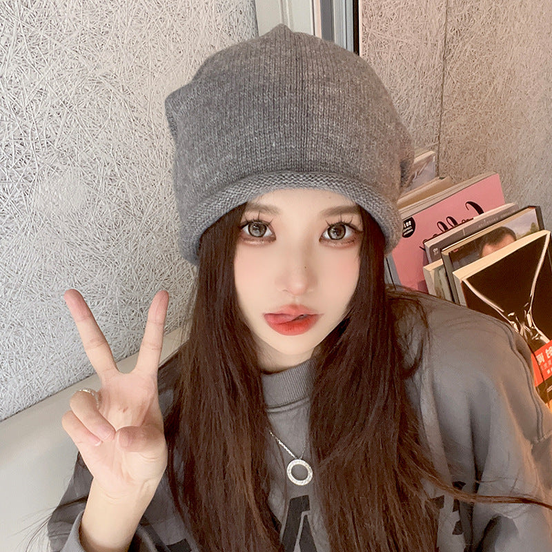 Gray knit beanie with silver necklace and peace sign pose, casual selfie