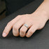 A stylish men's silver ring with a row of cubic zirconia, worn on a hand to showcase its elegant and contemporary design.