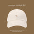 White baseball cap featuring tiny embroidered corgi dog logo against brown background