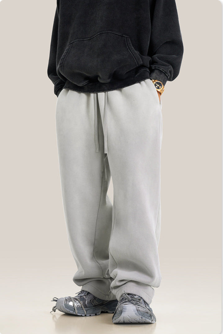 Person wearing light gray jogger pants with black hoodie featuring front pocket, styled with gray athletic shoes