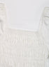 Close-up of the smocked detail on the white peplum blouse, showcasing the gathered elastic design.