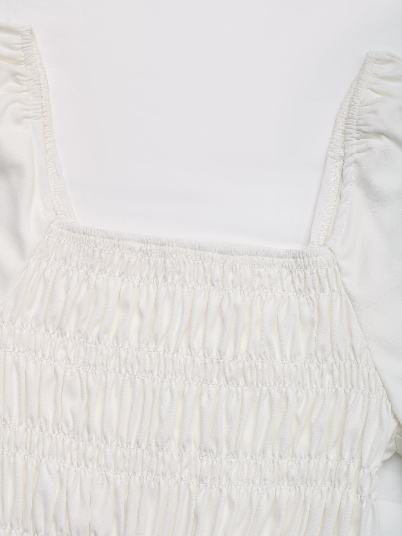 Close-up of the smocked detail on the white peplum blouse, showcasing the gathered elastic design.