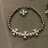 Elegant bracelet with polished silver beads, floral cross charms, and white pearls for a sophisticated touch.