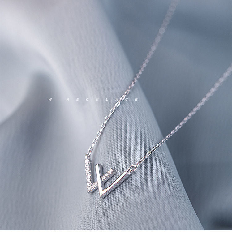 Silver W initial necklace styling photo against gray fabric with 'necklace' text overlay