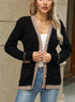 Black cardigan with beige trim, worn with white tank top and jeans, woman with blonde hair