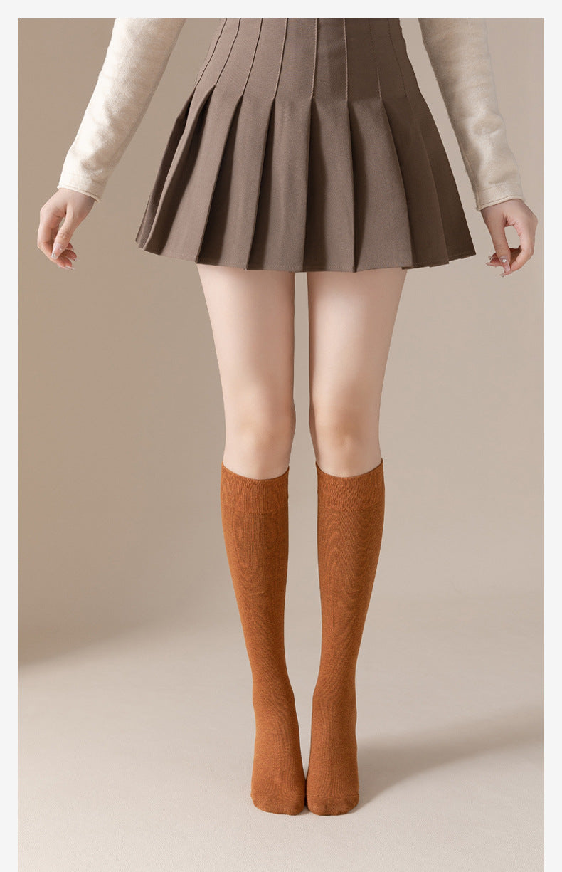 Front view of person in pleated skirt and camel brown knee-high socks