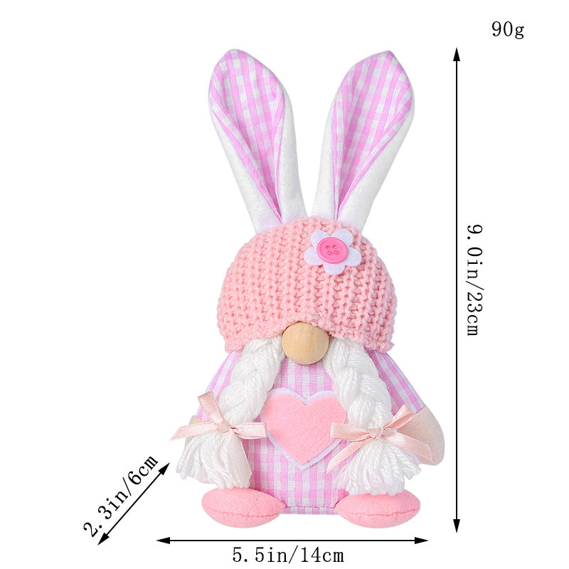 Pink bunny gnome plush with braided yarn hair, a heart detail, and a knit hat, standing at 23cm tall.