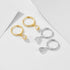 Gold and silver huggie hoops with teardrop crystal pendants arranged on geometric white background