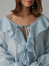 Light blue blouse with ruffled details on a neutral background