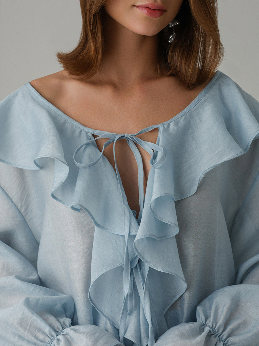 Light blue blouse with ruffled details on a neutral background