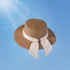 Chic brown wide brim straw hat for women, featuring a cream bow with a crystal accent. A perfect blend of elegance and sun protection for summer days.