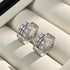 Pair of silver huggie hoops with double crystal rows displayed on white jewelry box cushion