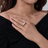 A woman wearing gold oval diamond engagement ring on her finger against black top background