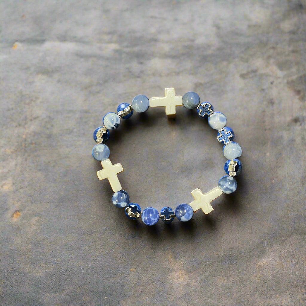 A stylish beaded bracelet with blue gemstone beads, white cross-shaped beads, and blue cross accents.