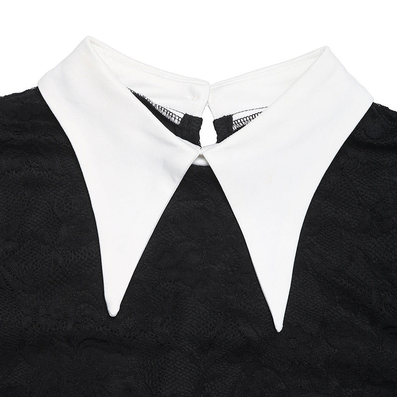 A close-up of the white pointed collar on a black lace dress, highlighting the fabric contrast and button closure.
