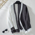 Flat lay of chunky knit cardigan in gray and white colorblock design, displayed with sunglasses