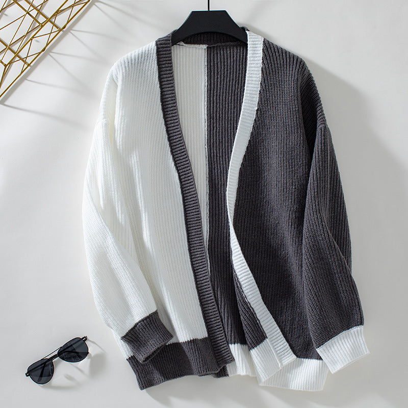 Flat lay of chunky knit cardigan in gray and white colorblock design, displayed with sunglasses