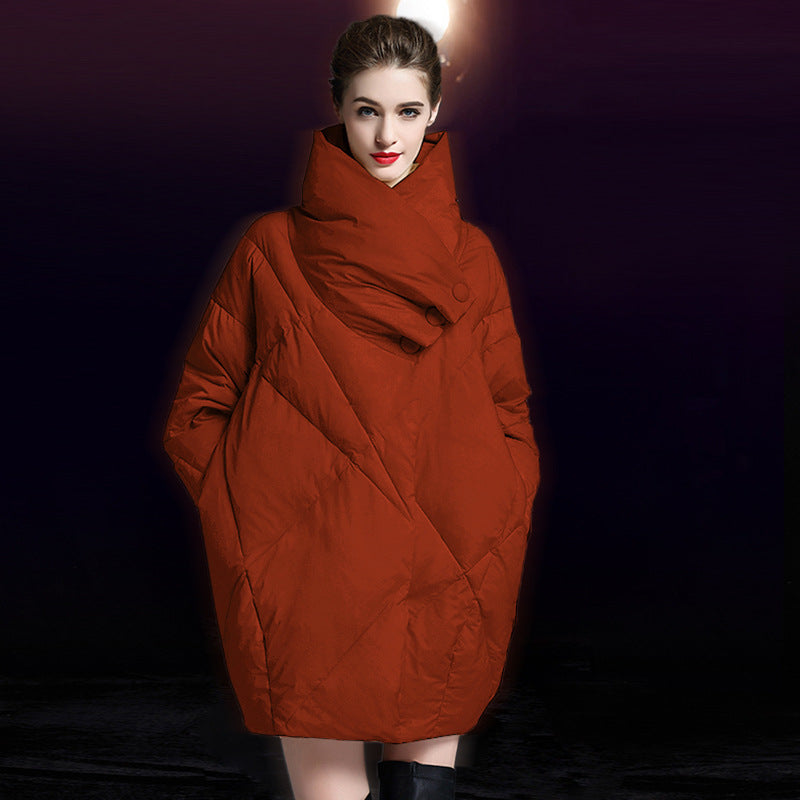 Model wearing rust-red oversized puffer coat with dramatic wrapped collar and button detail against dark background