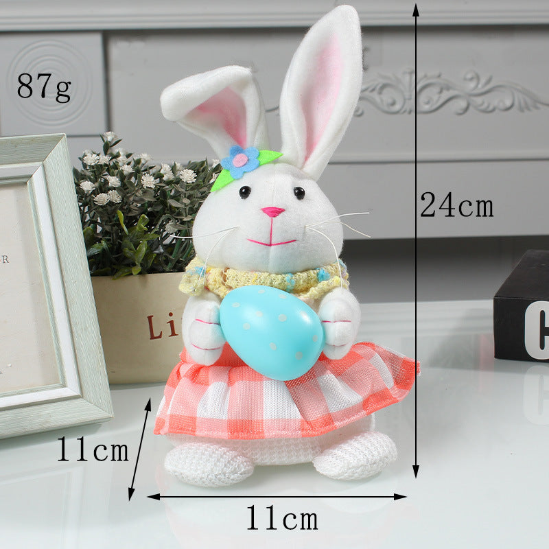 White plush bunny wearing a pink checkered dress and flower headband, holding a blue Easter egg, with labeled size dimensions of 24cm height and 11cm width.