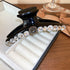 A glossy black hair claw clip adorned with large clear rhinestones and a vintage-inspired square gemstone centerpiece.